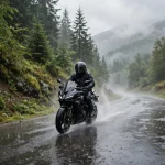Motorcycle rider in a full-face helmet riding through rain on a wet road
